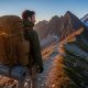 Hiker on mountain trail with versatile tactical backpack at sunrise