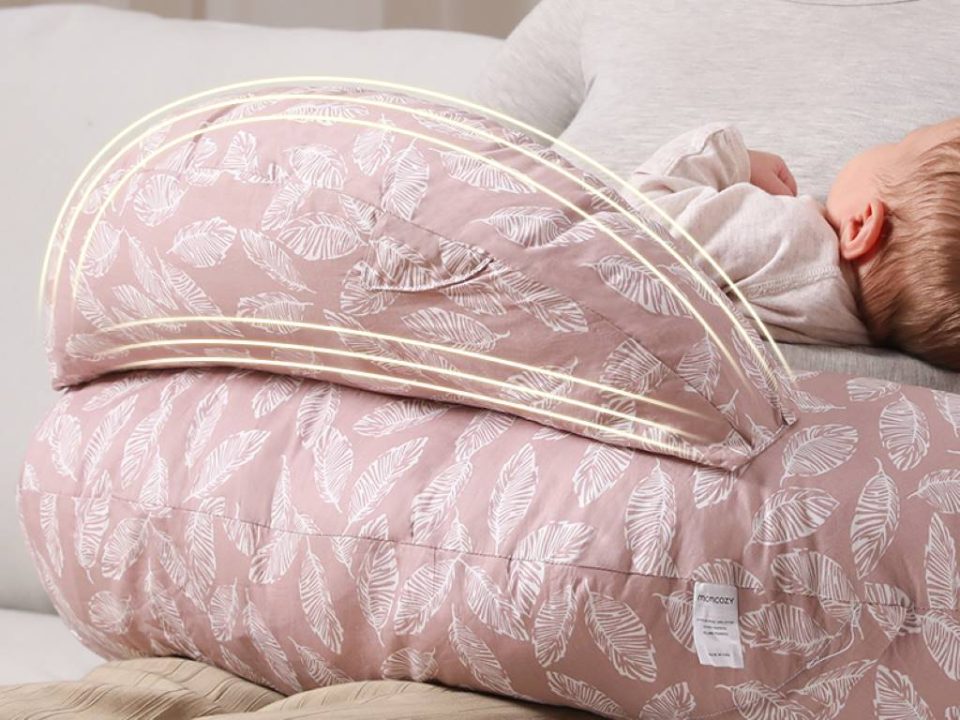 New mom smiling while breastfeeding comfortably with Momcozy Original nursing pillow around waist