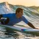 Surfer wearing a long sleeve rash guard paddling out through ocean waves