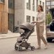 Compact baby stroller being pushed through a busy city sidewalk