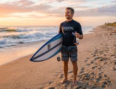 Surfer holding surf earplugs on a sunny Florida beach.