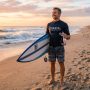 Surfer holding surf earplugs on a sunny Florida beach.