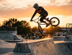 Professional BMX rider executing a high-flying tailwhip trick at a skatepark.