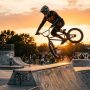 Professional BMX rider executing a high-flying tailwhip trick at a skatepark.