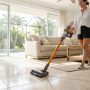 Modern stick vacuum cleaning tile flooring in a sunny Florida living room.