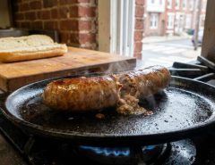 Whole golden Italian sausages cooking gently in skillet water